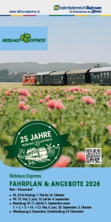 Roter Zug mit mehreren Waggons f&auml;hrt durch eine gr&uuml;ne Landschaft mit rosa Blumen im Vordergrund und H&uuml;geln im Hintergrund.