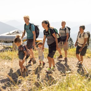 Famlilie bestehend aus 2 kleinen Kindern, Eltern und Großeltern wandert oberhalb der Sesselbahn.