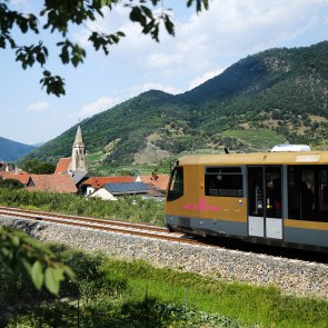 Der goldene Triebwagen der Wachaubahn fährt an einer Ortschaft vorbei