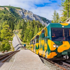 Der Salamanderzug der Schneeberg Sesselbahn fährt Bergwärts. Im Hintergrund sieht man den Gipfel des Schneebergs.