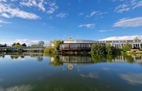 Ansicht des Geb&auml;udes der K&auml;sermacherwelt mit Teich im Vordergrund